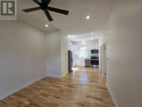 A spacious room with wooden flooring and a ceiling fan.