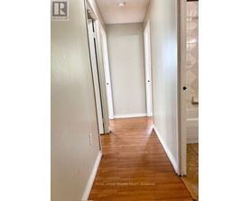 A hallway with wood floors and white walls.