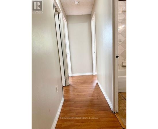 A hallway with wood floors and white walls.