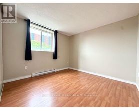 A room with wooden flooring and a window with black curtains.