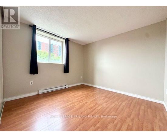A room with wooden flooring and a window with black curtains.