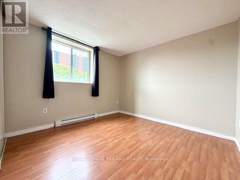 A room with wooden flooring and a window with black curtains.