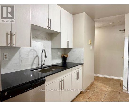 A kitchen with white cabinets and black countertops.