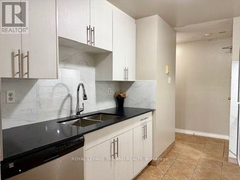 A kitchen with white cabinets and black countertops.