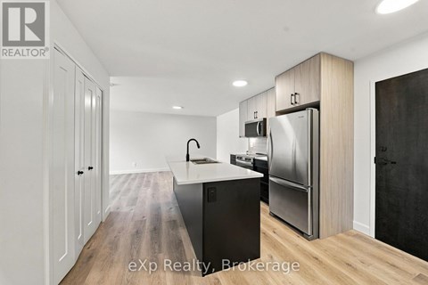 A modern kitchen with a refrigerator, sink, and cabinets.