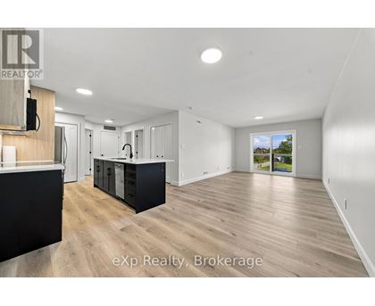 A spacious room with wooden flooring and white walls.