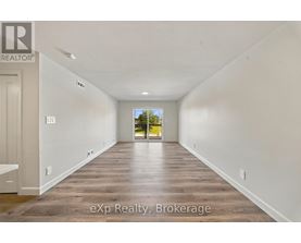 A long, empty hallway with wooden floors and white walls.