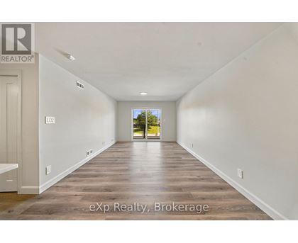 A long, empty hallway with wooden floors and white walls.