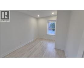 A white room with a window and wooden flooring.