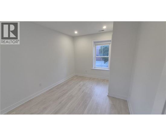 A white room with a window and wooden flooring.