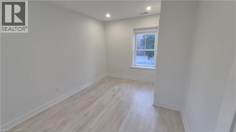 A white room with a window and wooden flooring.