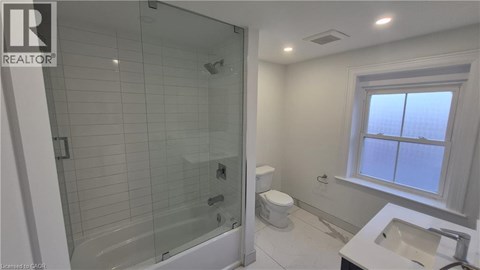 A bathroom with a glass shower stall, toilet, and sink.