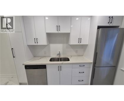 A kitchen with white cabinets and a stainless steel refrigerator.