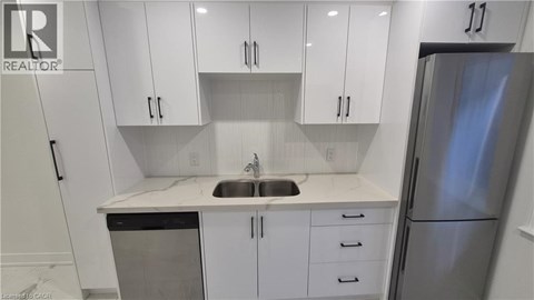 A kitchen with white cabinets and a stainless steel refrigerator.