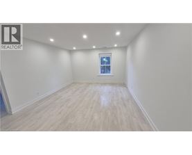 A spacious room with wooden flooring and a window.