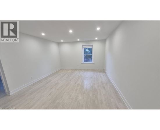A spacious room with wooden flooring and a window.