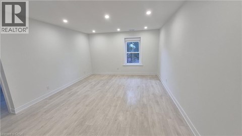 A spacious room with wooden flooring and a window.