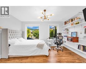 A bedroom with a large bed, a desk with a chair, and a window with a view of the outdoors.