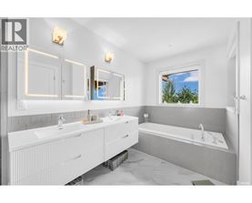 A bathroom with a large mirror and a window showing trees outside.