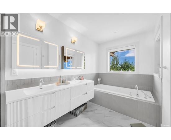 A bathroom with a large mirror and a window showing trees outside.