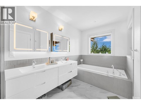 A bathroom with a large mirror and a window showing trees outside.