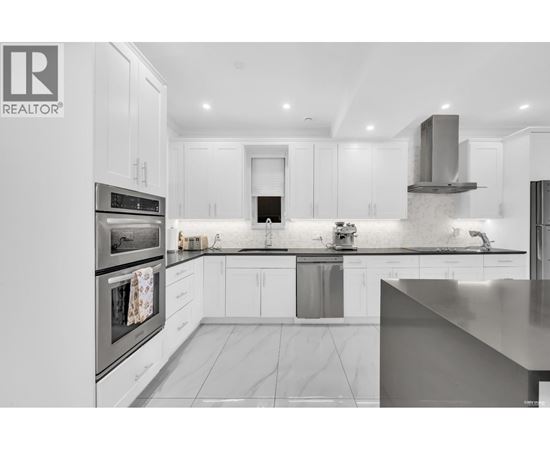 A modern kitchen with white cabinets and stainless steel appliances.