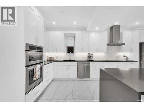 A modern kitchen with white cabinets and stainless steel appliances.