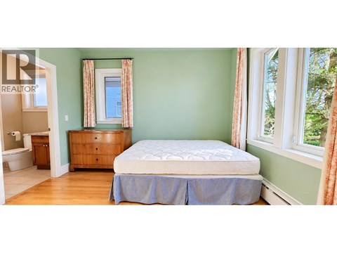 A bedroom with a bed, dresser, and window.
