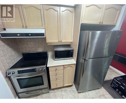 A kitchen with wooden cabinets and a stainless steel refrigerator.