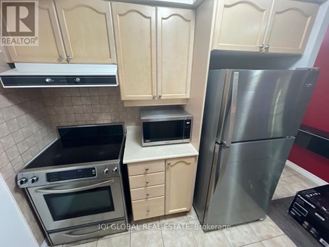 A kitchen with wooden cabinets and a stainless steel refrigerator.