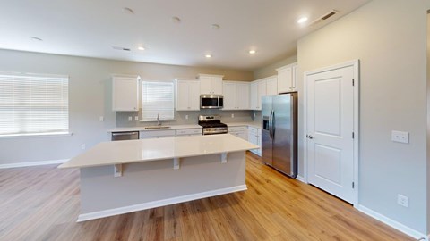 A kitchen with a refrigerator, oven, and cabinets.