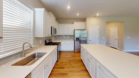 A kitchen with white cabinets and a wooden floor.