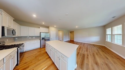 A kitchen with white cabinets and a wooden floor.