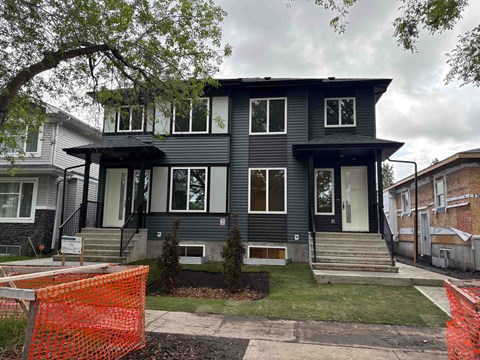 A grey house with a black roof and a white door.