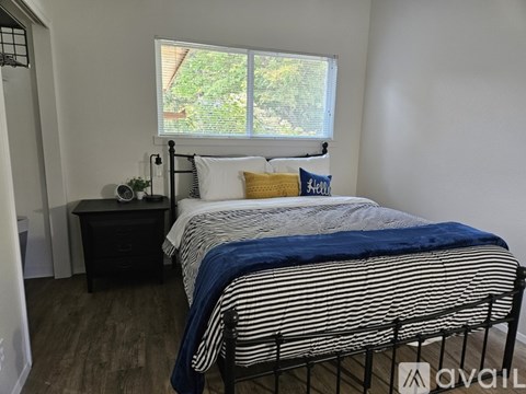 A bedroom with a bed, nightstand, and window.