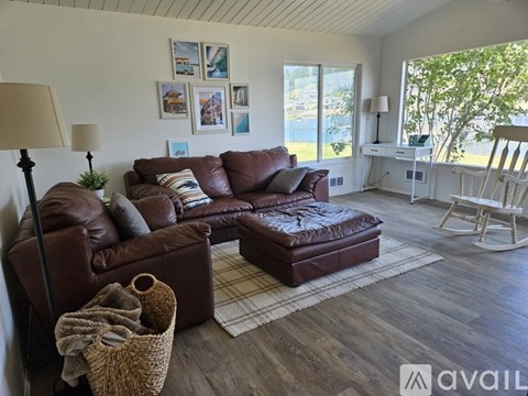 A living room with a brown leather couch and a brown ottoman.
