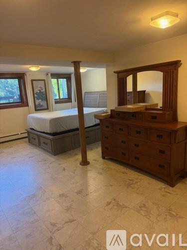 A bedroom with a large bed and a wooden dresser.