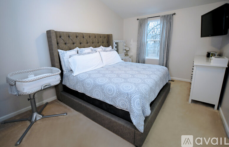 A bedroom with a large bed and a white chair.