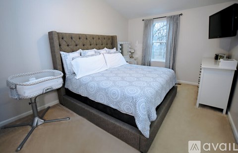 A bedroom with a large bed and a white chair.