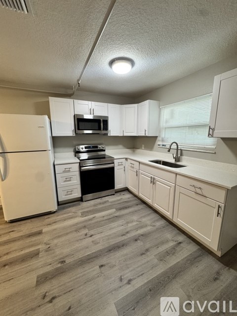 A kitchen with a white fridge, microwave, and oven.