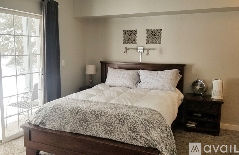 A bedroom with a large bed and a balcony with a chair.