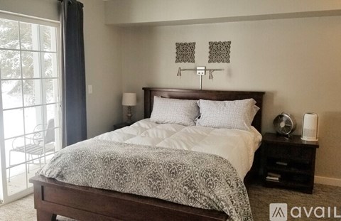 A bedroom with a large bed and a balcony with a chair.