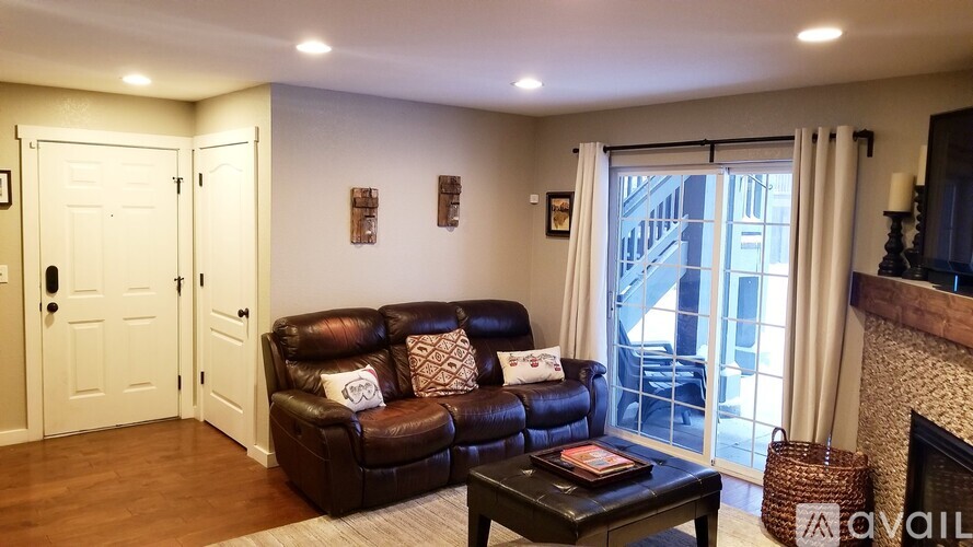A living room with a brown leather couch and a fireplace.