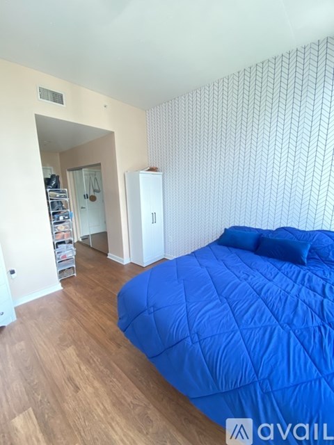 A bedroom with a blue bedspread and a white cabinet.
