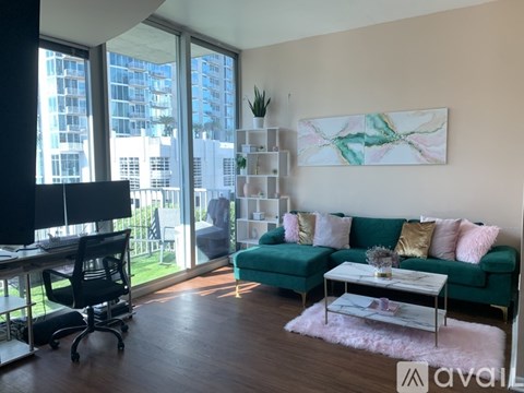 A living room with a green couch and a painting on the wall.