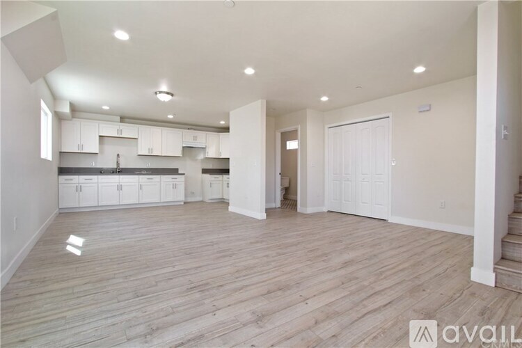 A spacious room with wooden flooring and white walls.