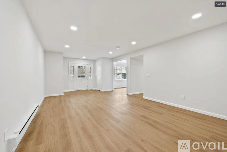 A spacious room with wooden flooring and white walls.