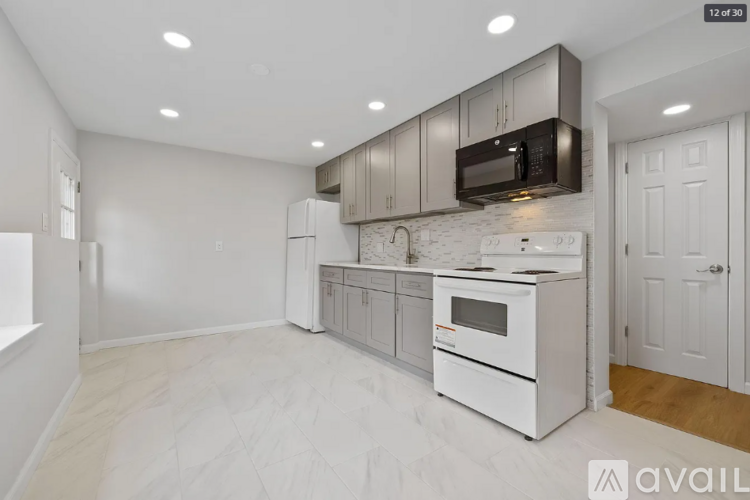 A modern kitchen with white cabinets and appliances, and a wooden floor.