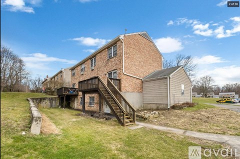 A house with a brown brick exterior and a staircase leading to the entrance.