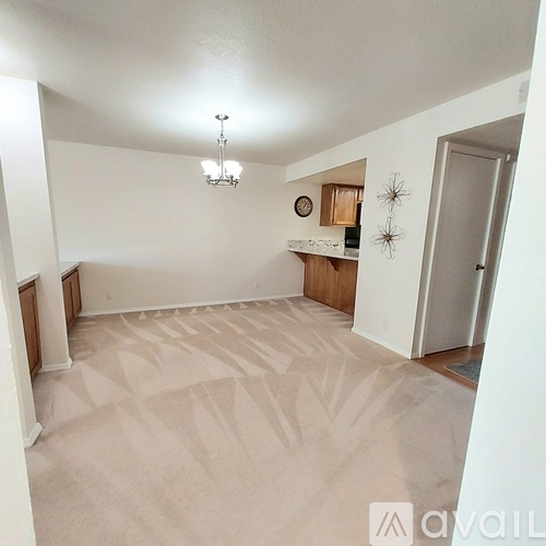 A spacious room with a patterned carpet and a chandelier hanging from the ceiling.